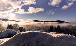 Der Bayerwald zeigt sein winterliches Gesicht mit einem Schnee bedeckten Gipfel und Wolken.